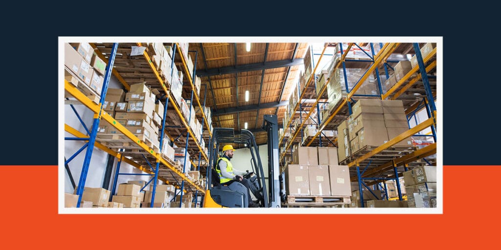 Warehouse worker driving a forklift to take a pallet full of boxes off of a warehouse rack